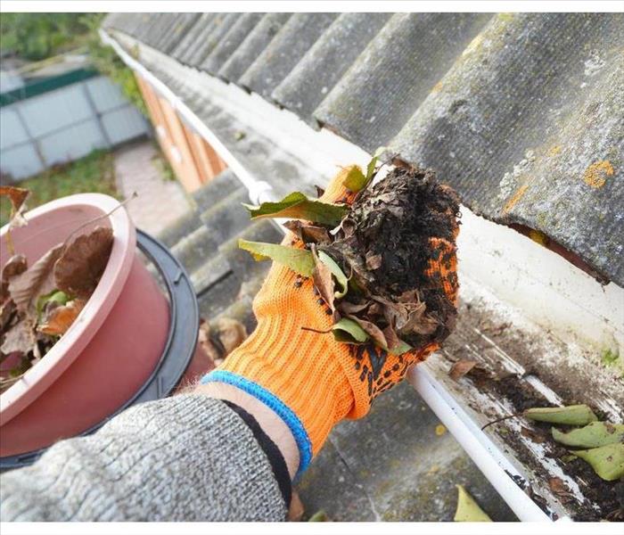 Hand cleaning a gutter with leaves